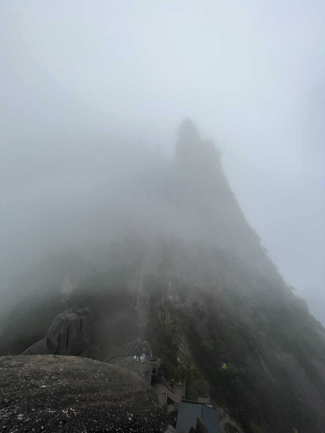 霧の中にそびえる天都峰の岩峰と、ふもとの登山道