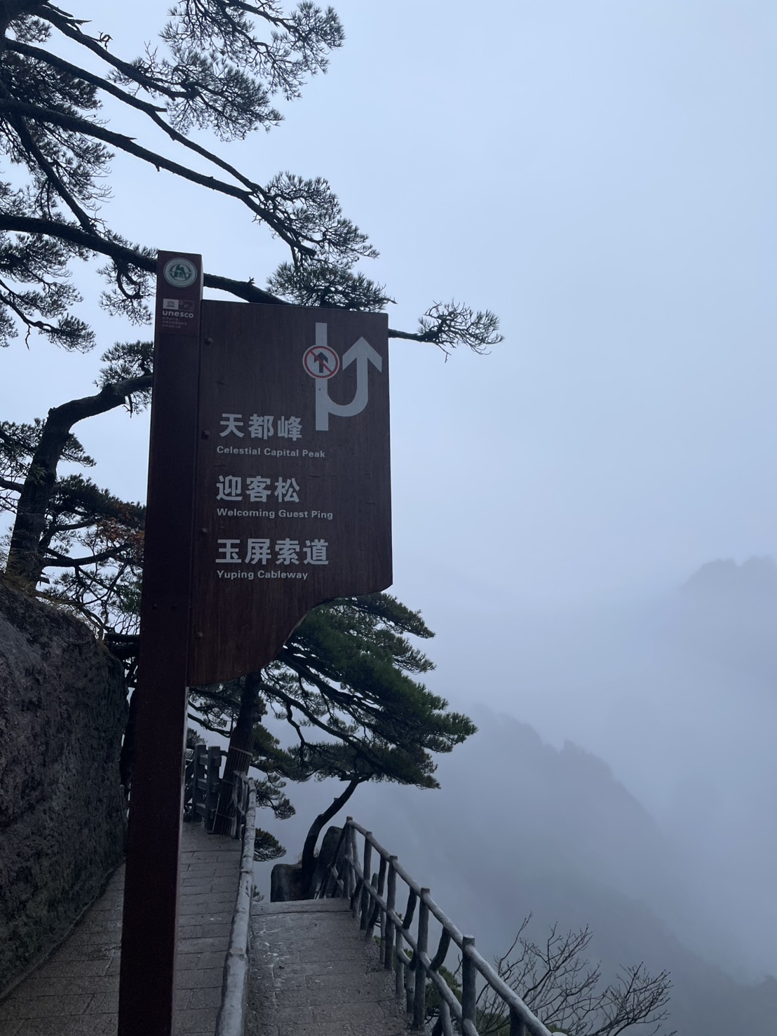 天都峰・迎客松・玉屏索道を示す黄山の道案内の看板と霧の谷