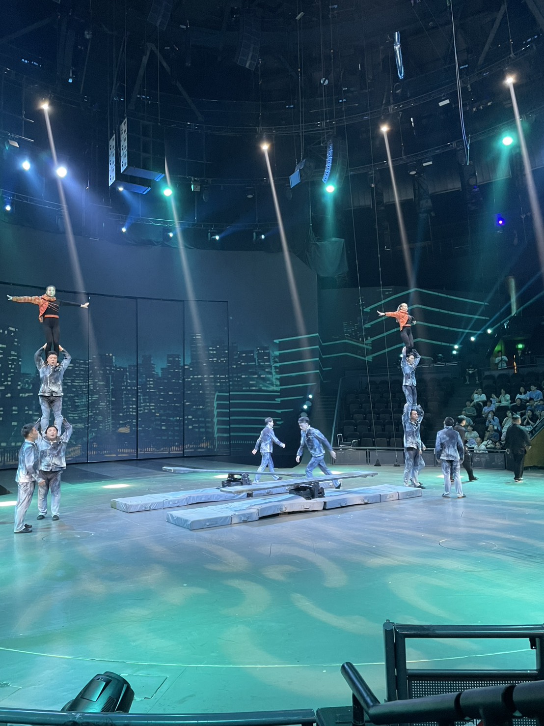 上海雑技団ERA時空の旅2、近未来の夜景をバックに人の肩の上に立つ演者たち